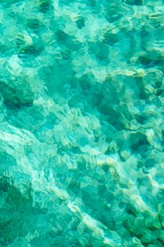 Close-up of clear turquoise water with abstract patterns and vibrant shades of green.