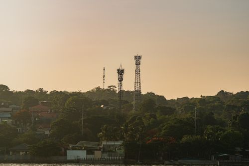 Free Scenic view of communication towers amidst a tropical landscape during sunset, showcasing lush greenery and urban architecture. Stock Photo