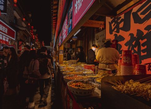 Bustling night market with street food vendors and illuminated red lanterns, capturing lively atmosphere.