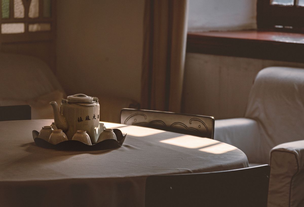 A serene table setting with a teapot and cups, bathed in gentle afternoon light, evokes warmth and tranquility.