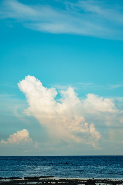 Free A peaceful ocean scene featuring vibrant blue skies and dramatic clouds over calm waters. Stock Photo