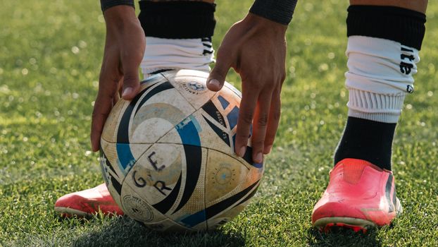 Close-up of a soccer player setting the ball on a grassy field, ready to take a shot.