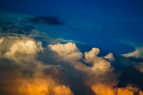 Free Vivid sunset clouds with warm orange and deep blue hues creating a dramatic sky view. Stock Photo