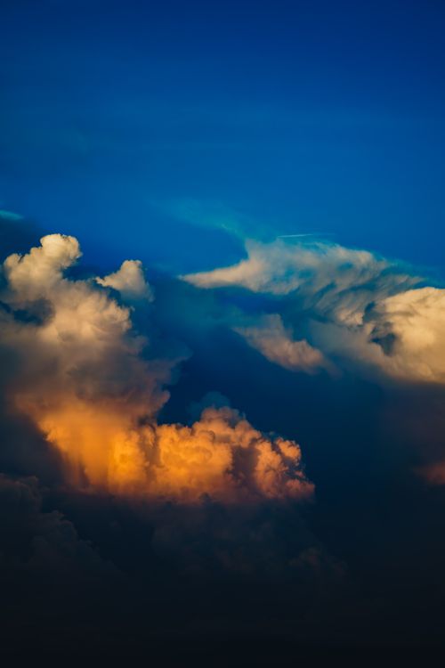 Free Vibrant sunset clouds with dramatic lighting contrast sharply against a deep blue sky. Stock Photo