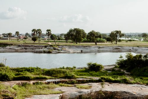 Free Peaceful river scene with lush greenery and distant urban view in Kaduna, Nigeria. Stock Photo