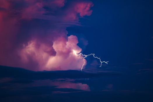 A vivid display of lightning illuminating colorful storm clouds during twilight.