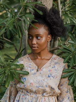 A portrait of a woman in a floral dress surrounded by lush greenery, conveying elegance and serenity.