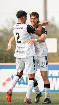 Two soccer players celebrating a goal on an outdoor field, showing camaraderie.