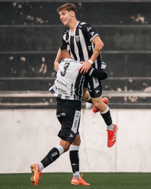 Free Two male soccer players in black jerseys celebrate a goal with a mid-air embrace on the field. Stock Photo