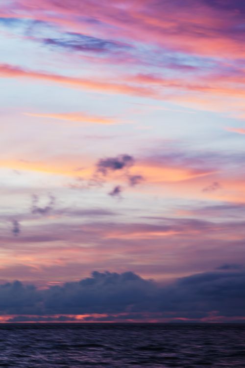 Free Stunning sunset scene showcasing vibrant colors reflecting over calm sea waters. Stock Photo