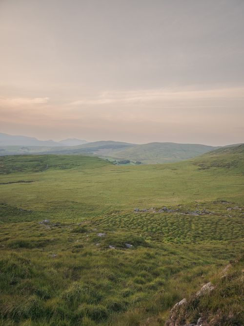 Free Tranquil view of lush green hills and valleys during sunset in Ireland. Stock Photo