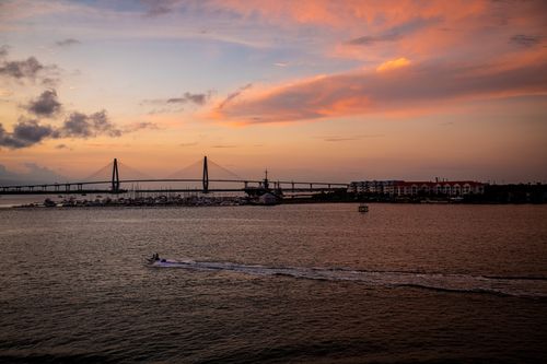Free Beautiful sunset view of a bridge spanning over a calm sea with colorful skies. Stock Photo