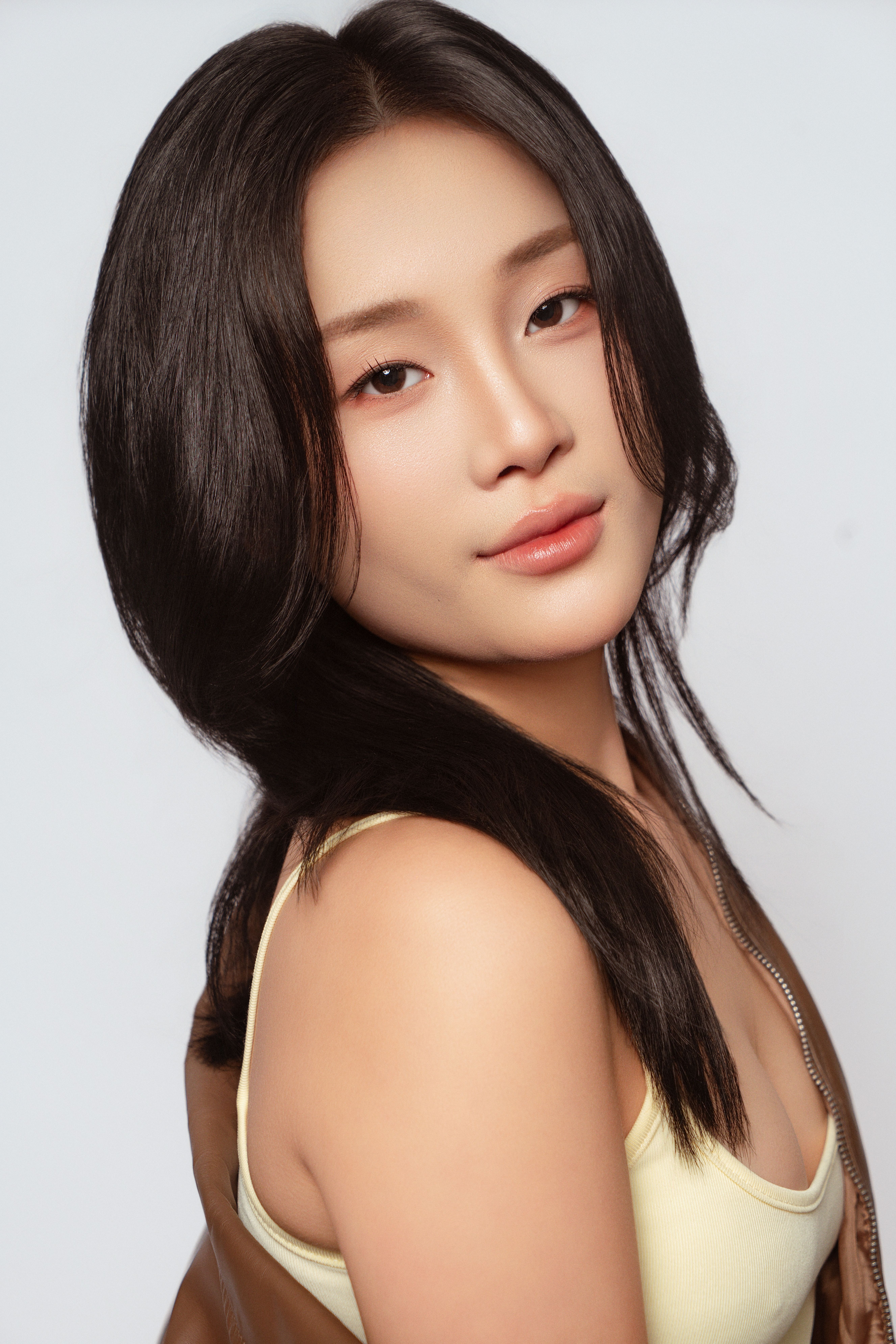 Artistic portrait of a young Asian woman with a gentle smile and flawless skin.