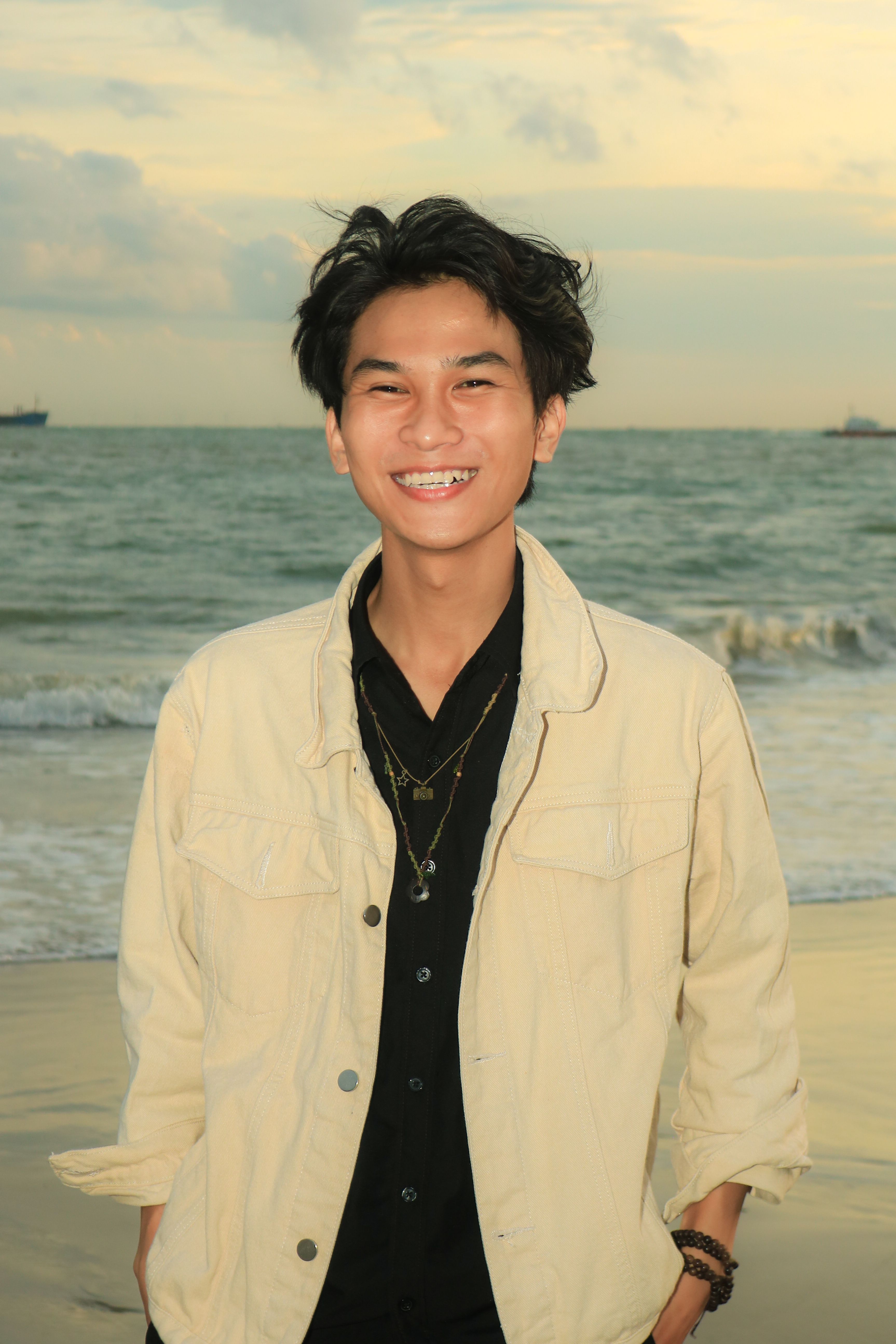 A cheerful young man enjoying a beautiful sunset at the beach.