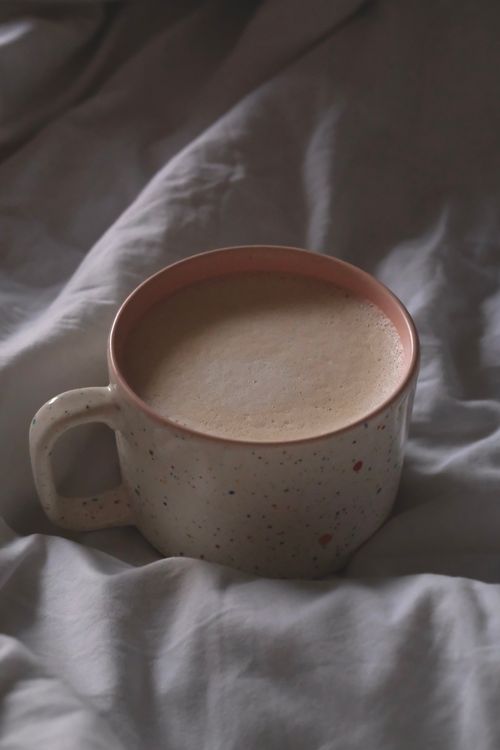 Free Warm coffee in a speckled mug nestled in soft bedding, creating a cozy atmosphere. Stock Photo