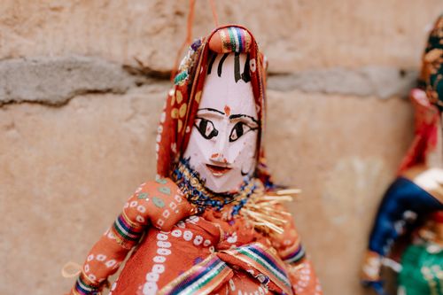 Free Colorful Rajasthani puppet in vibrant attire hanging on a rustic wall in Rajasthan, India. Stock Photo