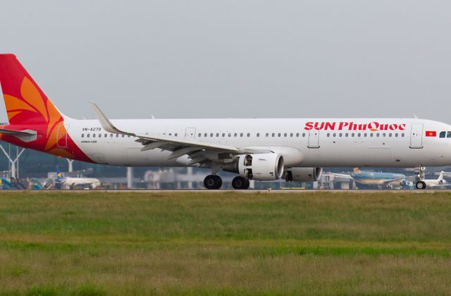 An Airbus A321 branded 'SUN Phu Quoc' on the runway at an airport with visible hangars and other aircraft. — arriving in Phu Quoc