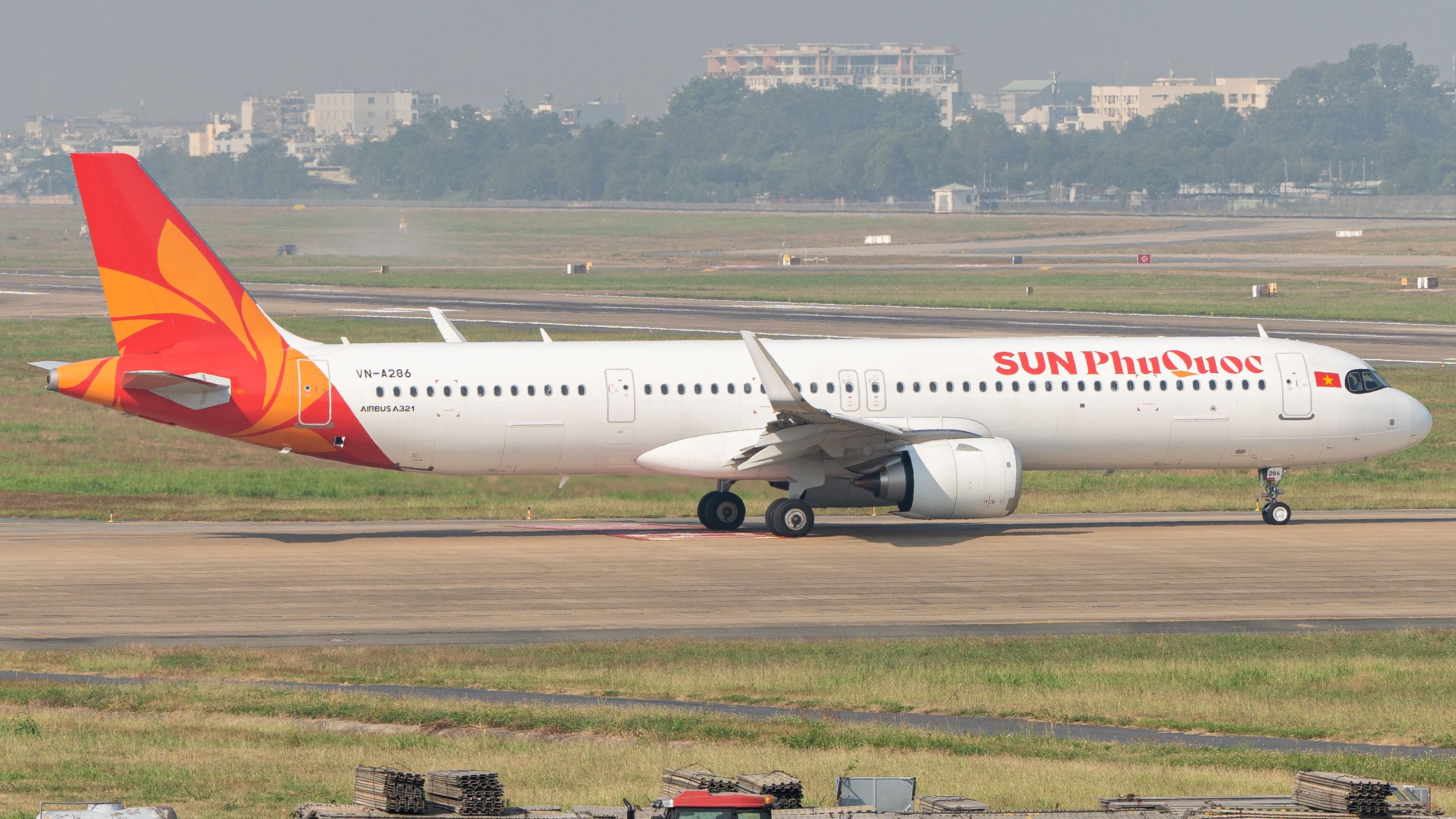 Airbus A321 on a sunny runway, ready for takeoff, showcasing vibrant tail design.