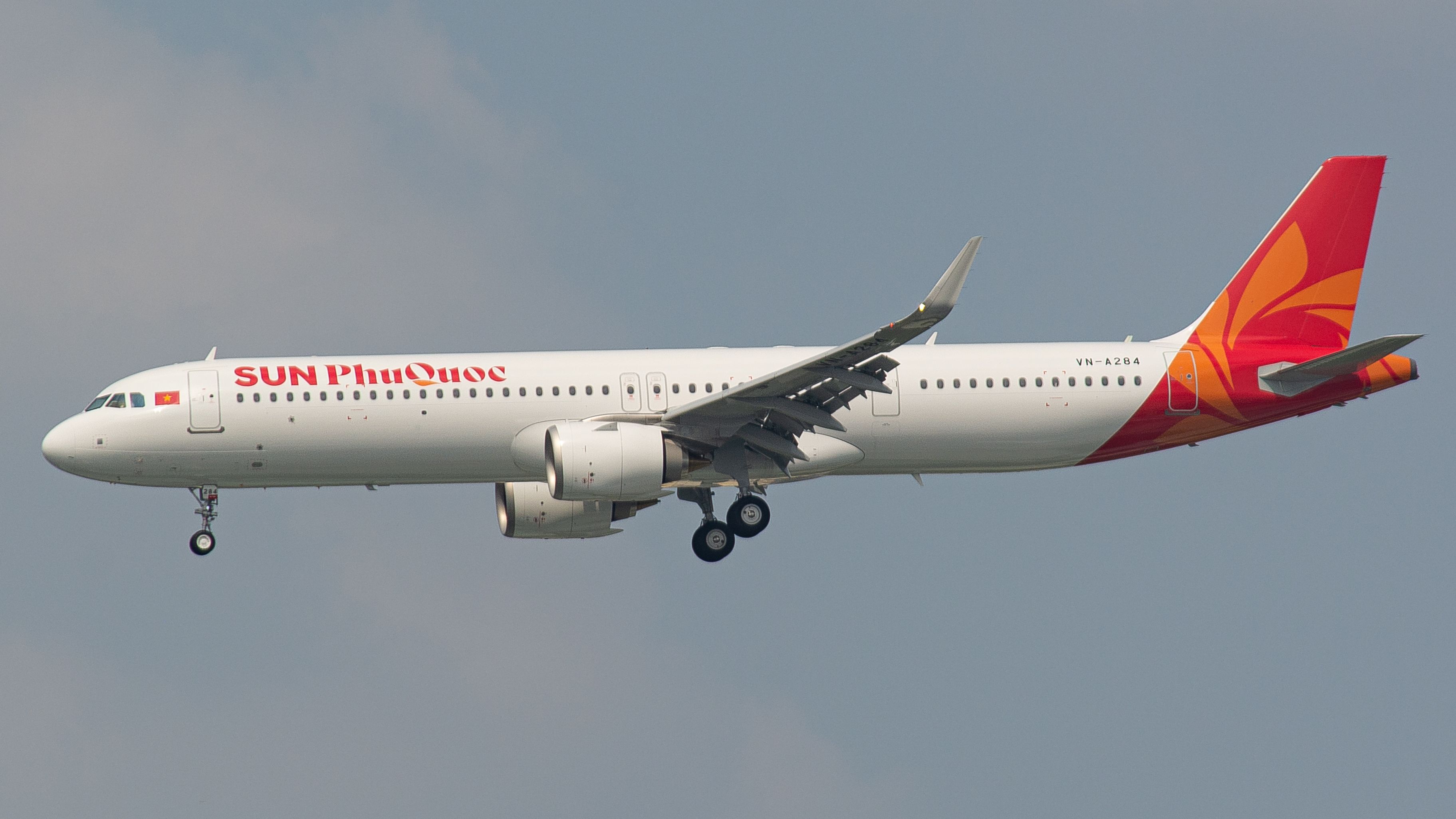 Sun Phu Quoc Airbus A321 flying mid-air with landing gear extended against a clear sky.