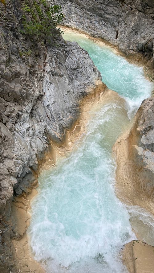 Free Pristine turquoise stream flowing between rugged rocky canyon walls offers a serene natural scene. Stock Photo