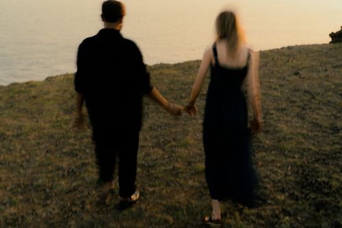 Free A couple walks hand-in-hand by the tranquil lake, embracing a serene sunset. Stock Photo