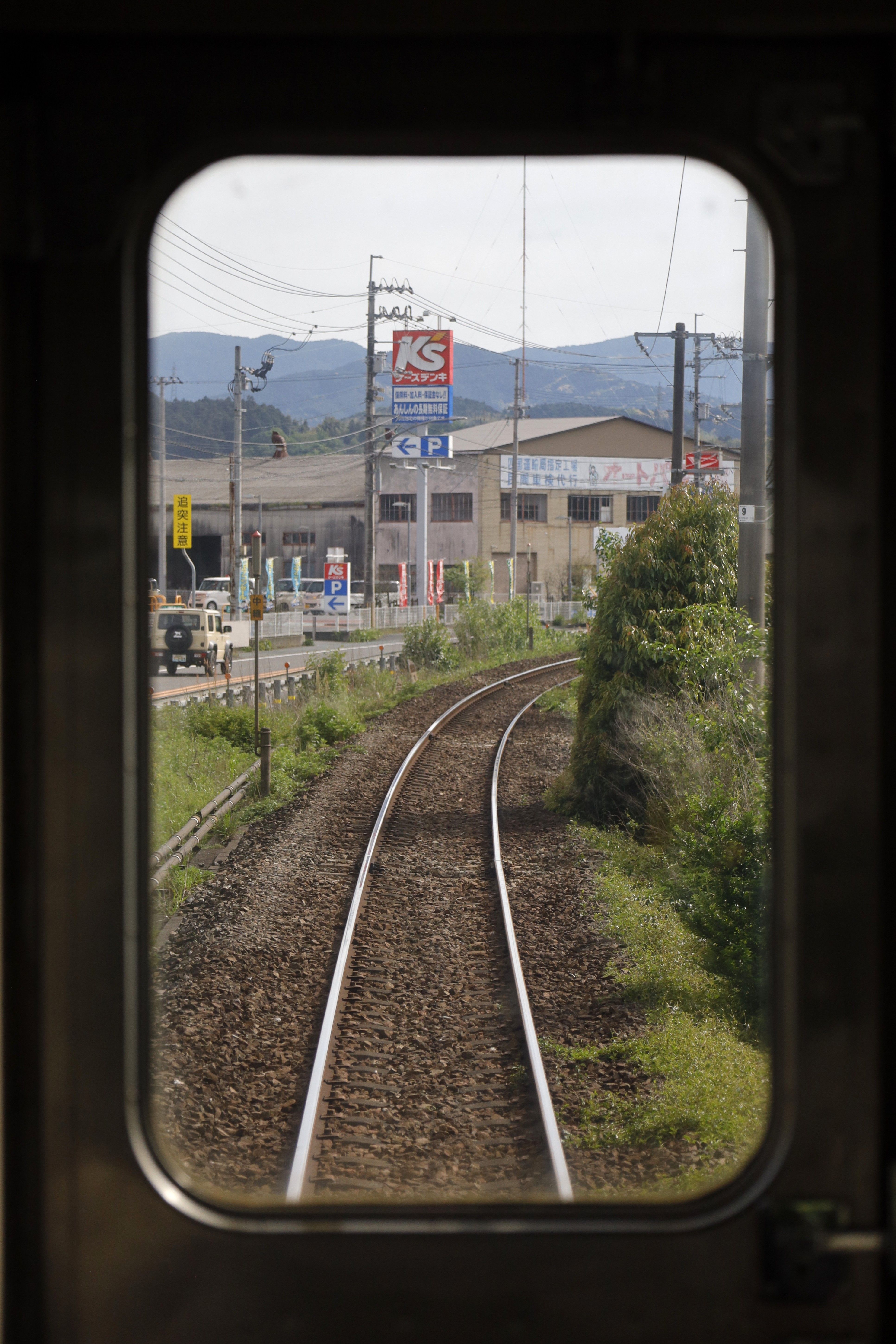 View of railway tracks through train window in Ozu, Japan, capturing the scenery and landscape.