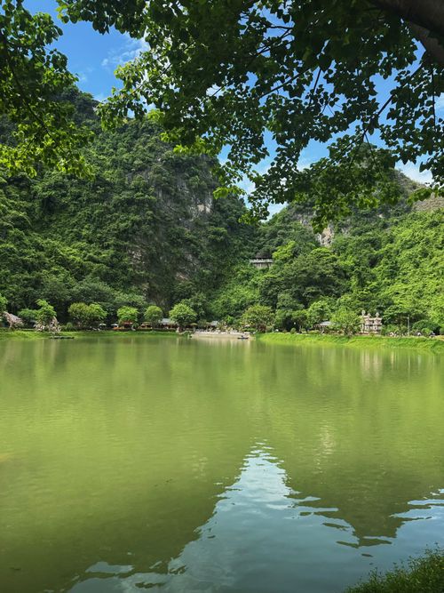 Free Tranquil lake surrounded by lush hills and vibrant greenery on a sunny day. Stock Photo