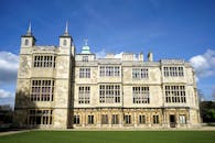 蔚蓝的天空下，一座优雅的哥特式豪宅拥有复杂的石立面和郁郁葱葱的绿色草坪