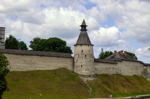 Free Stone fortress tower with conical roof against a backdrop of lush greenery and clouds, exuding historic charm. Stock Photo