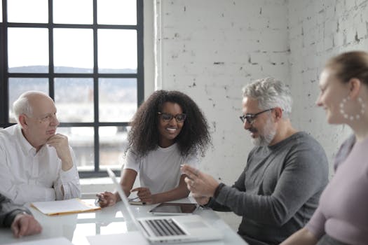 A diverse group of colleagues happily collaborating in a modern office setting with natural light.