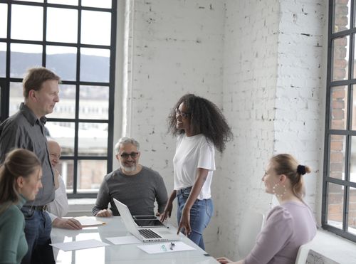 Free Group of multiethnic colleagues discussing business project while working on startup strategy during meeting with laptop and tablet smiling happily Stock Photo