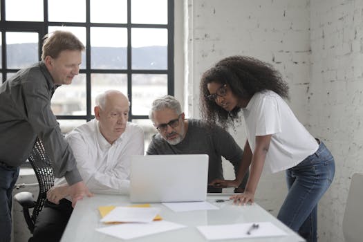 Business team collaborating in a modern office space, reviewing information on a laptop.