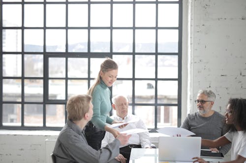 Multiracial coworkers of different ages in casual clothes discussing work plan and current issues at table with laptop in office