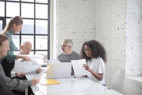 Free Focused multiracial coworkers of different ages in casual clothes brainstorming on new business ideas and company strategy while sitting at table in creative workspace Stock Photo