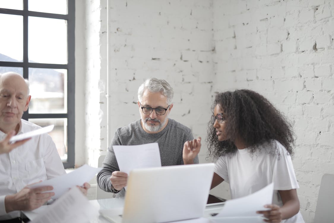Free Young African American woman discussing new project with senior male colleague at meeting in boardroom Stock Photo