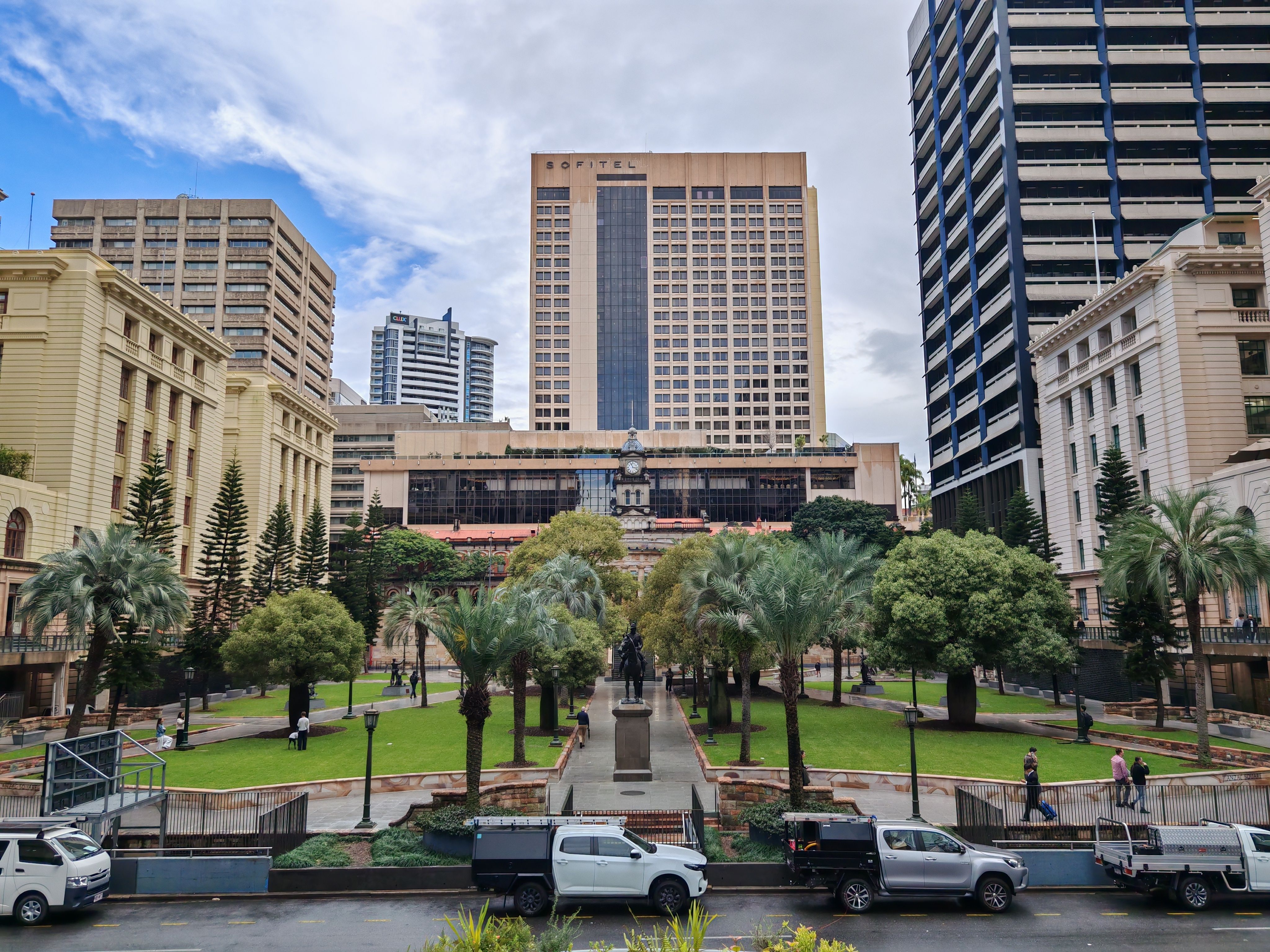 A scenic view of urban Brisbane with Sofitel Hotel and surrounding buildings, showcasing greenery and city life.