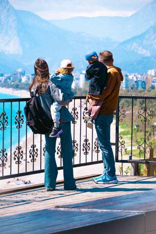 Free A family of four enjoying a scenic view of the beach and city skyline. Stock Photo