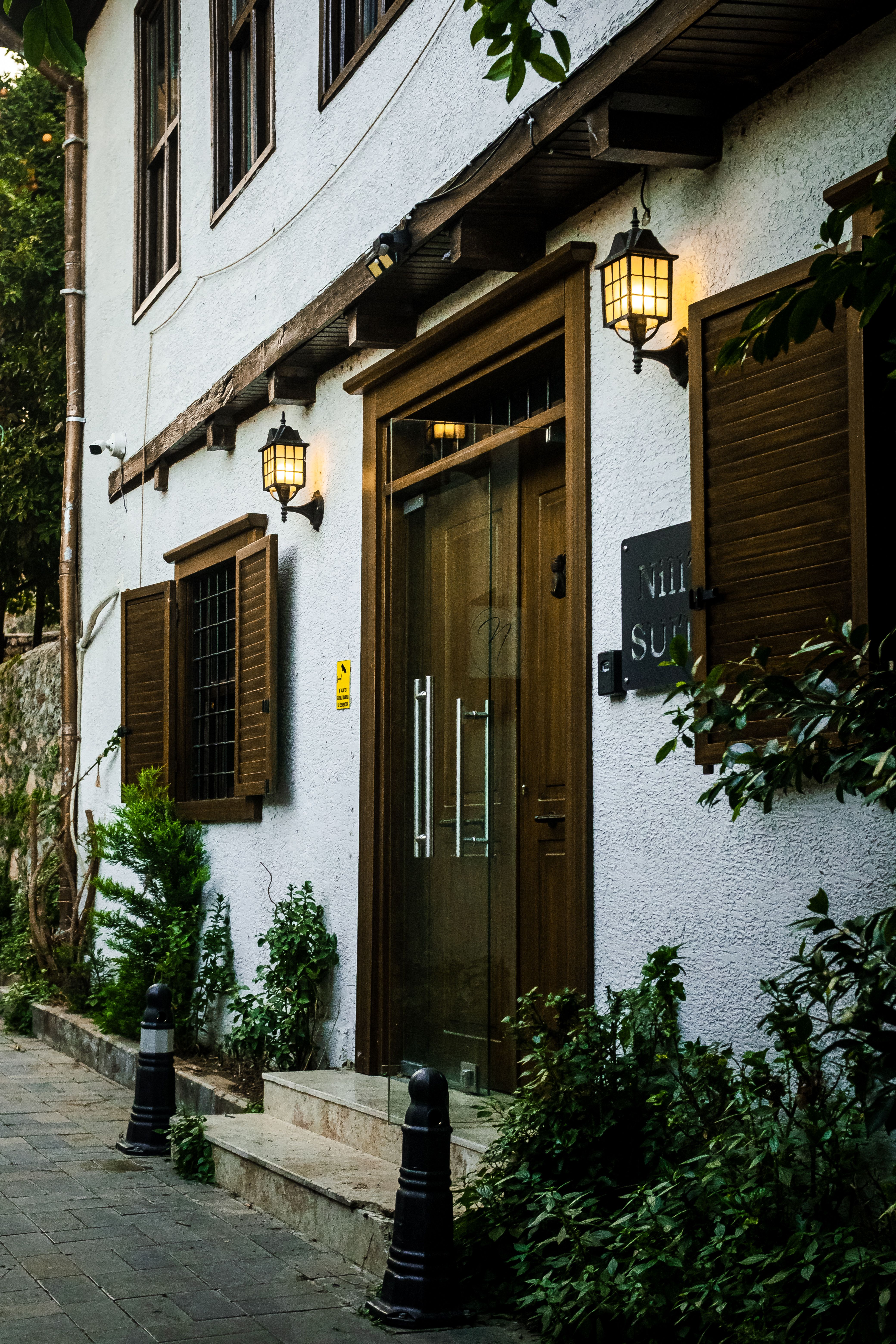 A rustic villa exterior with wooden shutters and lanterns adds charm during twilight. Ideal for architectural or travel themes.