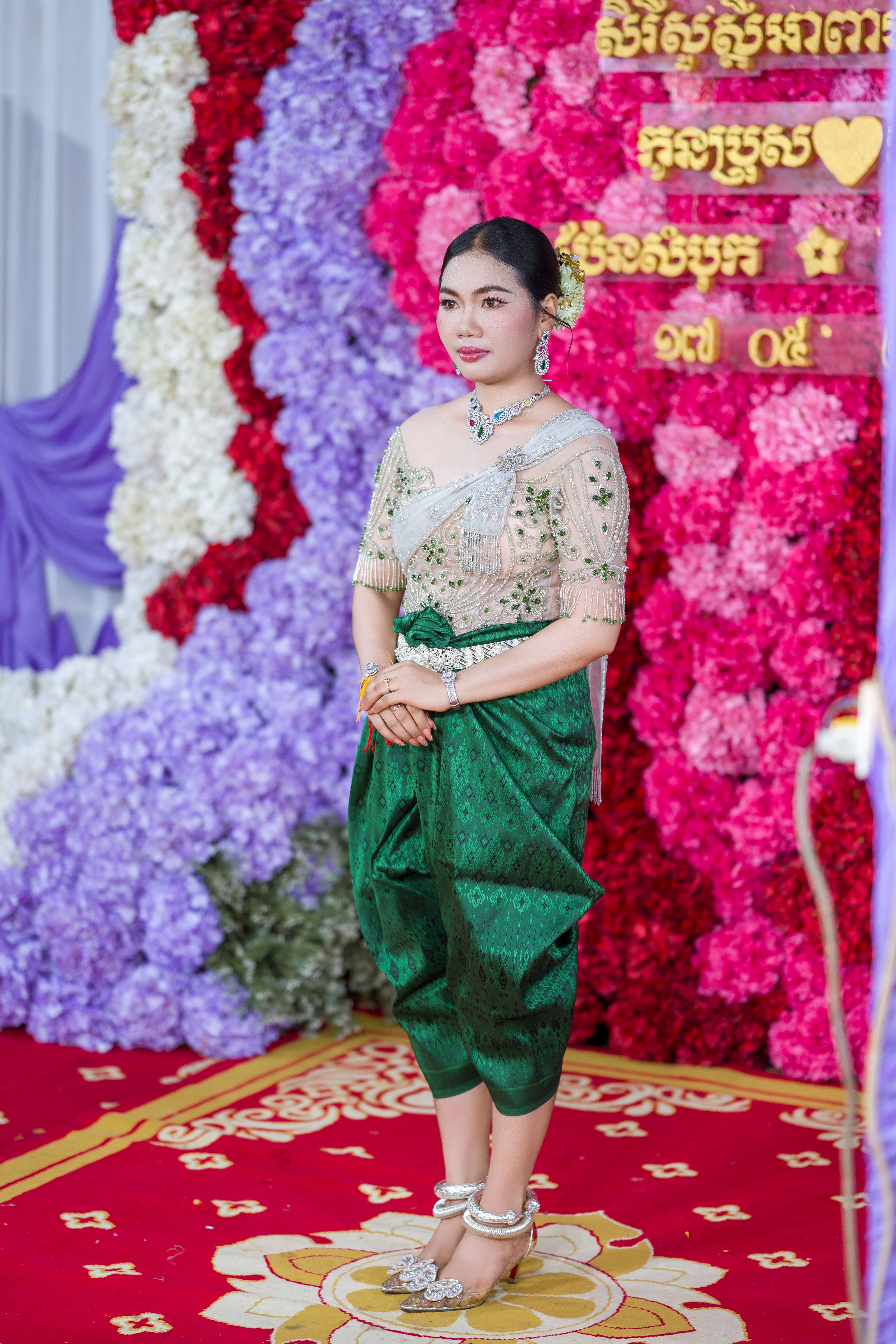 Elegant Cambodian woman in traditional Khmer wedding attire at a colorful ceremony.
