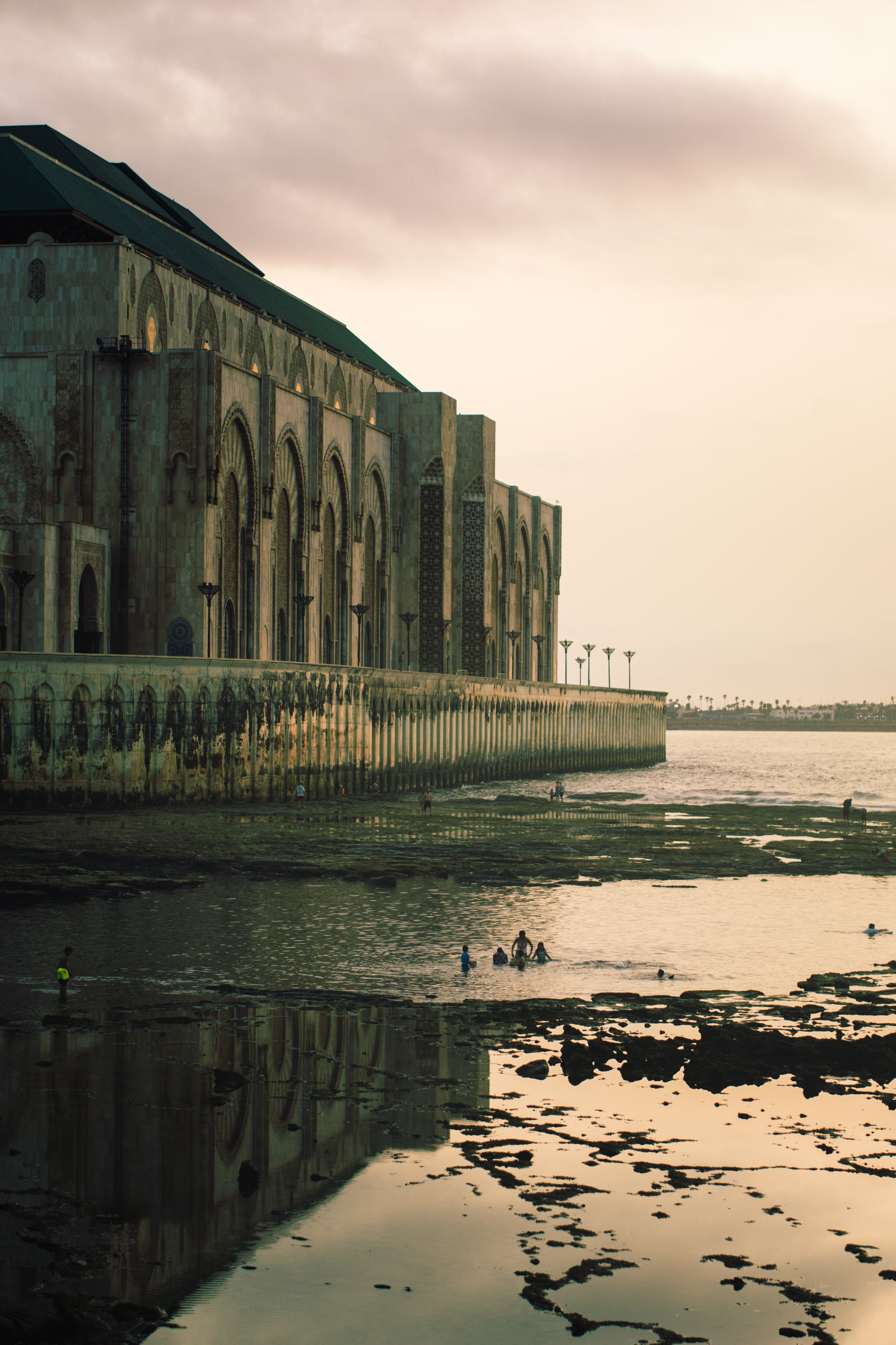 Dramatic sunset at Hassan II Mosque, Casablanca, with reflections and ocean view.