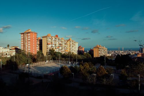 Free Scenic view of urban buildings and park with distant sea in the background during sunset. Stock Photo