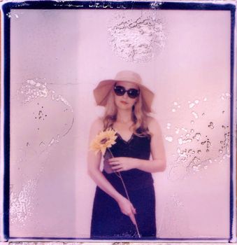 Artistic polaroid of woman in sunglasses holding sunflower, vintage style.
