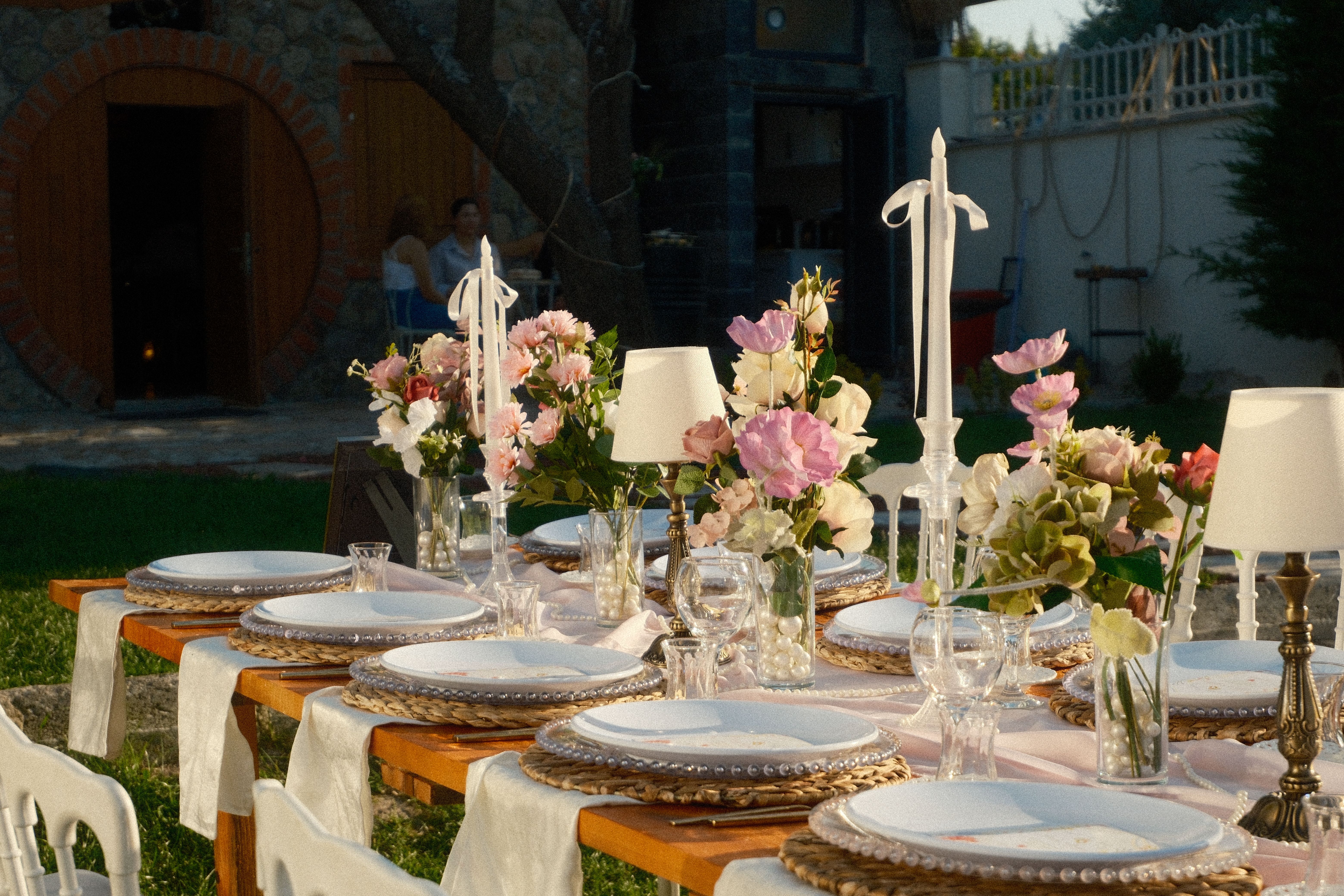 Beautifully arranged outdoor garden party table with floral centerpieces and elegant place settings.