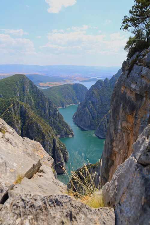 Free Stunning aerial view of a deep canyon with a winding river, lush greenery, and rocky cliffs. Stock Photo