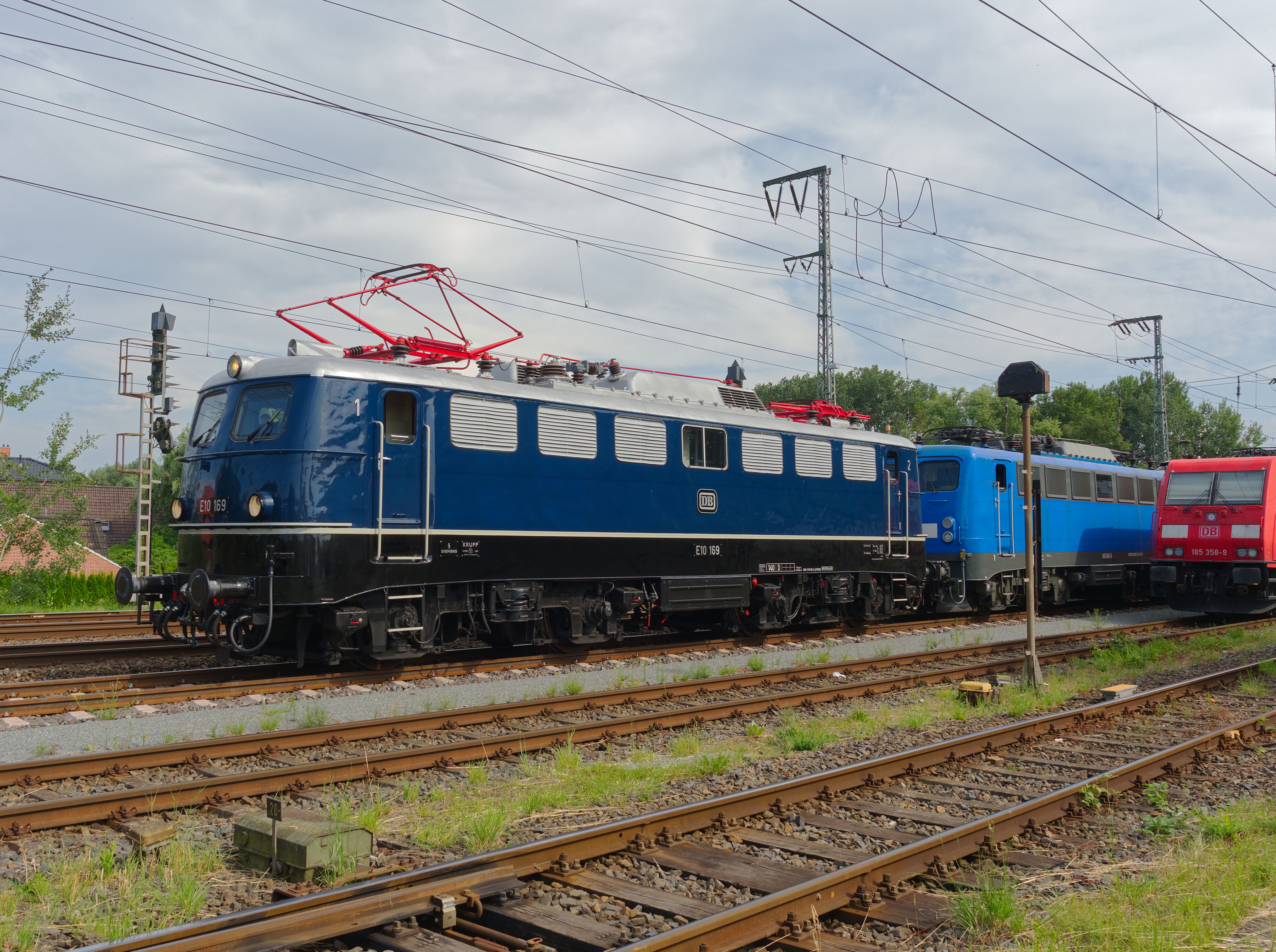 Classic and modern electric locomotives on tracks under a clear sky.