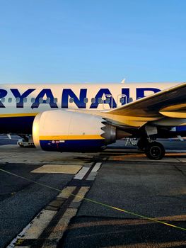 Close-up of a Ryanair airplane on tarmac, showcasing its engine and fuselage.