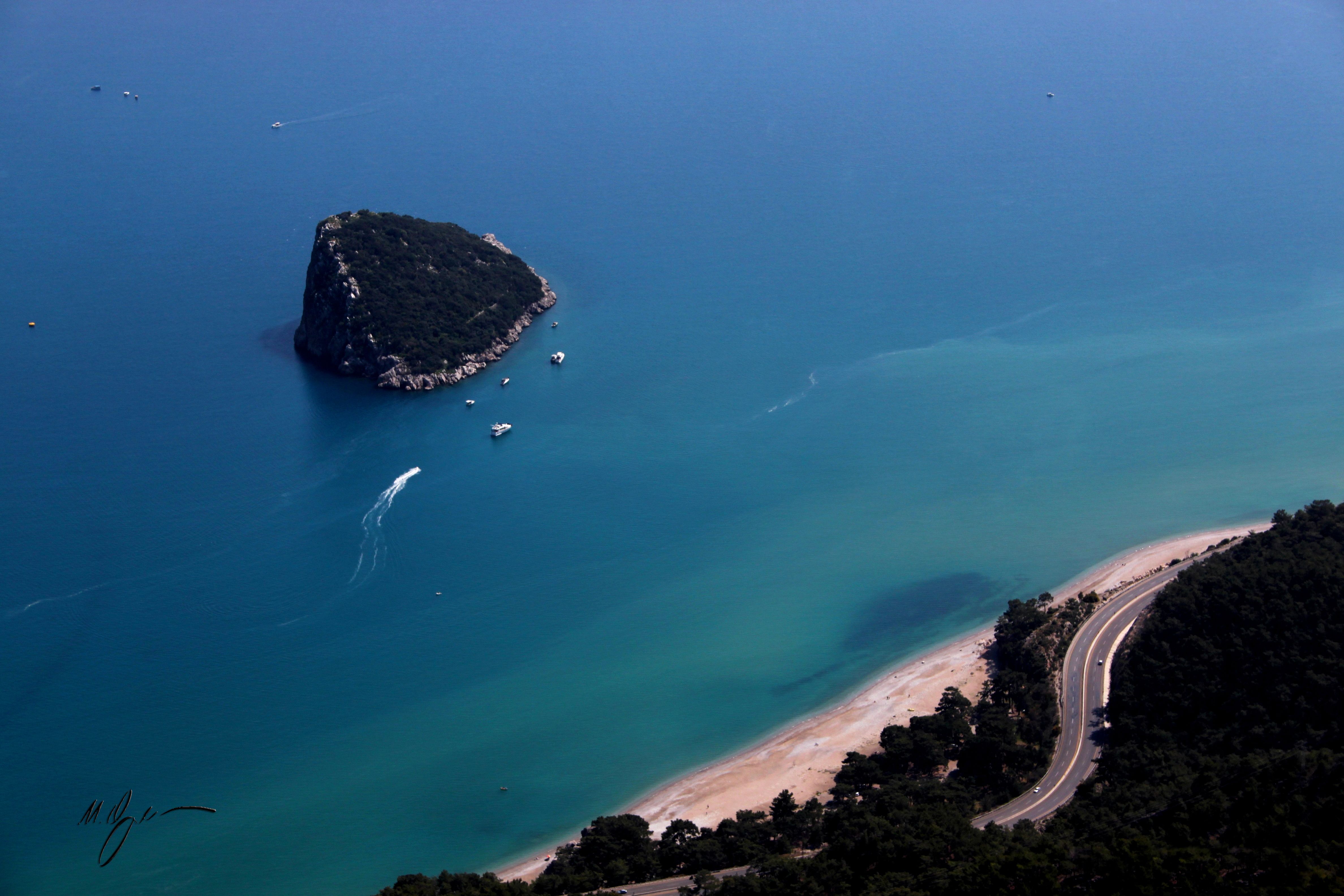A breathtaking aerial view of an island surrounded by turquoise water and a beachside road.