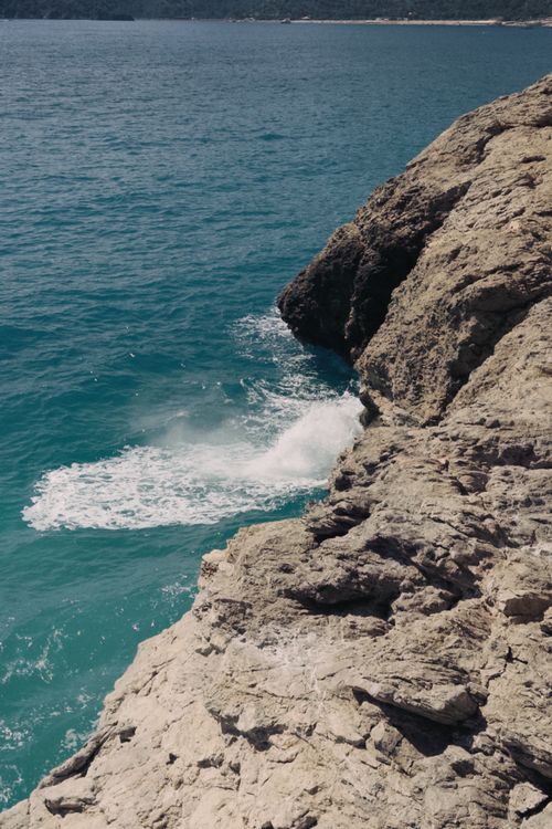 Free A scenic view of ocean waves crashing against rugged cliffs under a sunny sky. Stock Photo