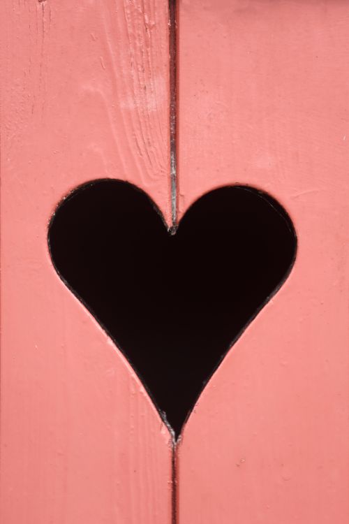 Free A charming heart-shaped cutout in a pink wooden fence, perfect for romantic themes. Stock Photo