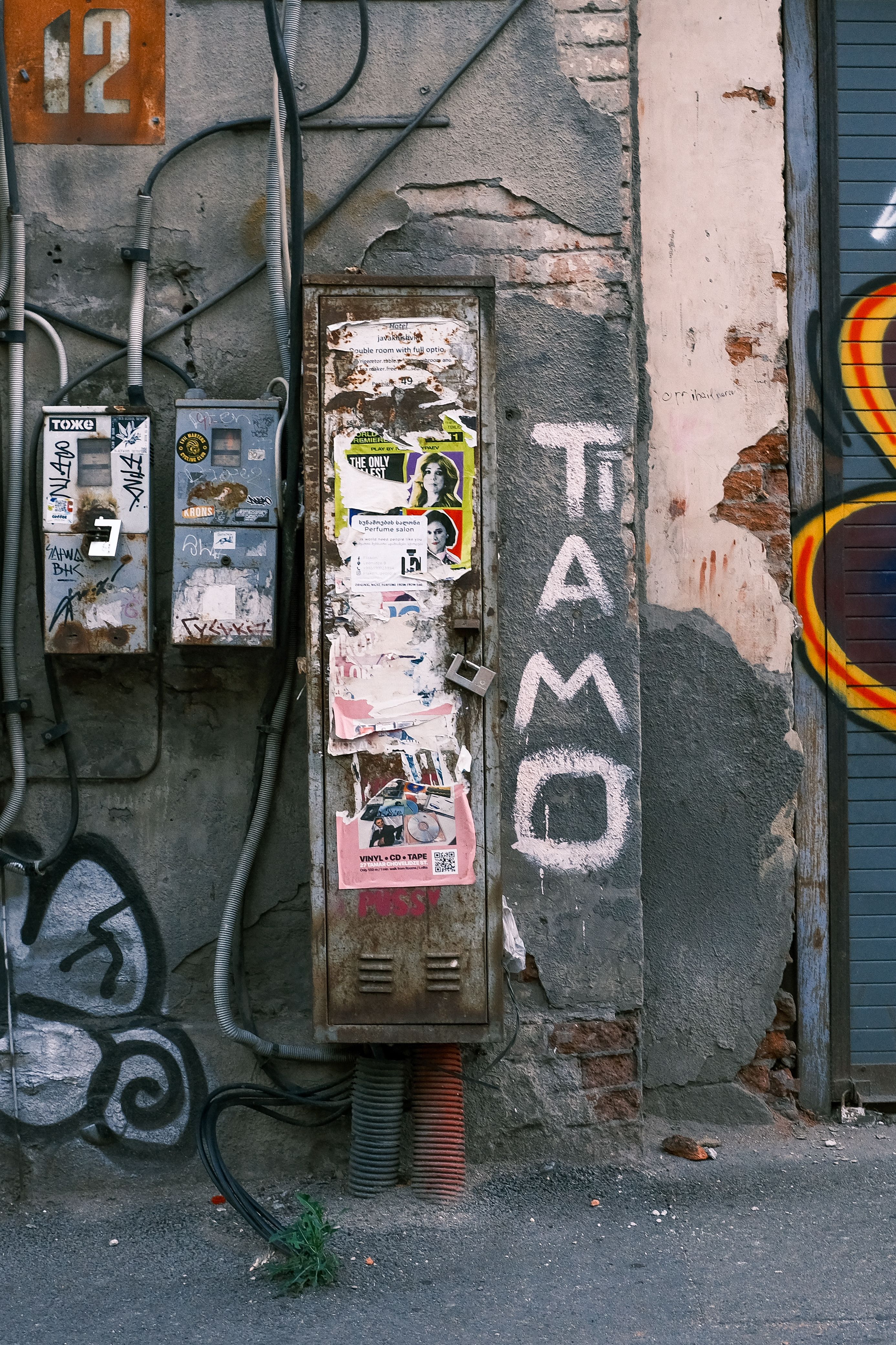 Vibrant urban scene with graffiti and street art on a worn wall featuring electrical boxes.